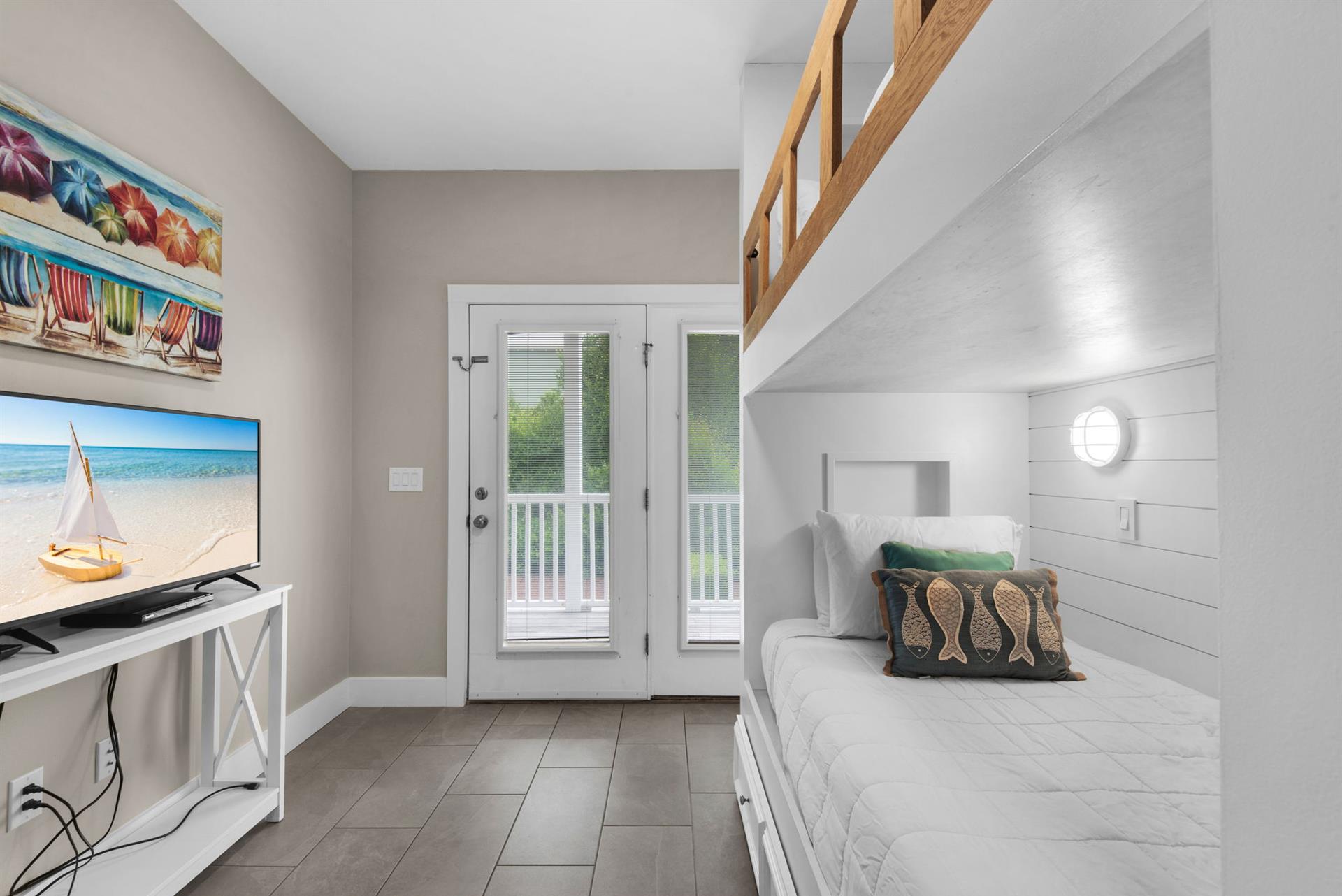 Unwind in the bunk room with cheerful beach decor, a comfortable daybed, and direct balcony access. Perfect for cozy evenings or quiet moments.
