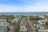 Elevated perspective showcasing a coastal community with beach access. The property is situated among treelined streets and residential homes, just moments from pristine turquoise waters.