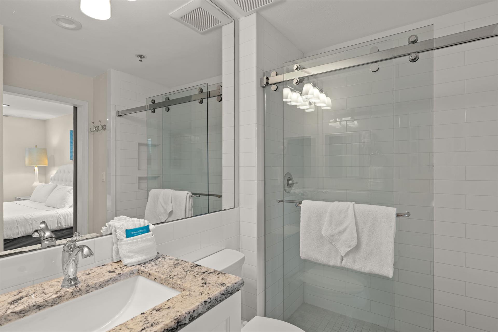Spacious walkin shower with sleek glass doors, elegant subway tile, and soft towels waiting for you. The granite vanity and modern fixtures create a luxurious space to refresh and unwind.