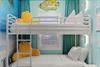 Beachthemed bunk room awaits with cheerful yellow pillows, and playful ocean artwork