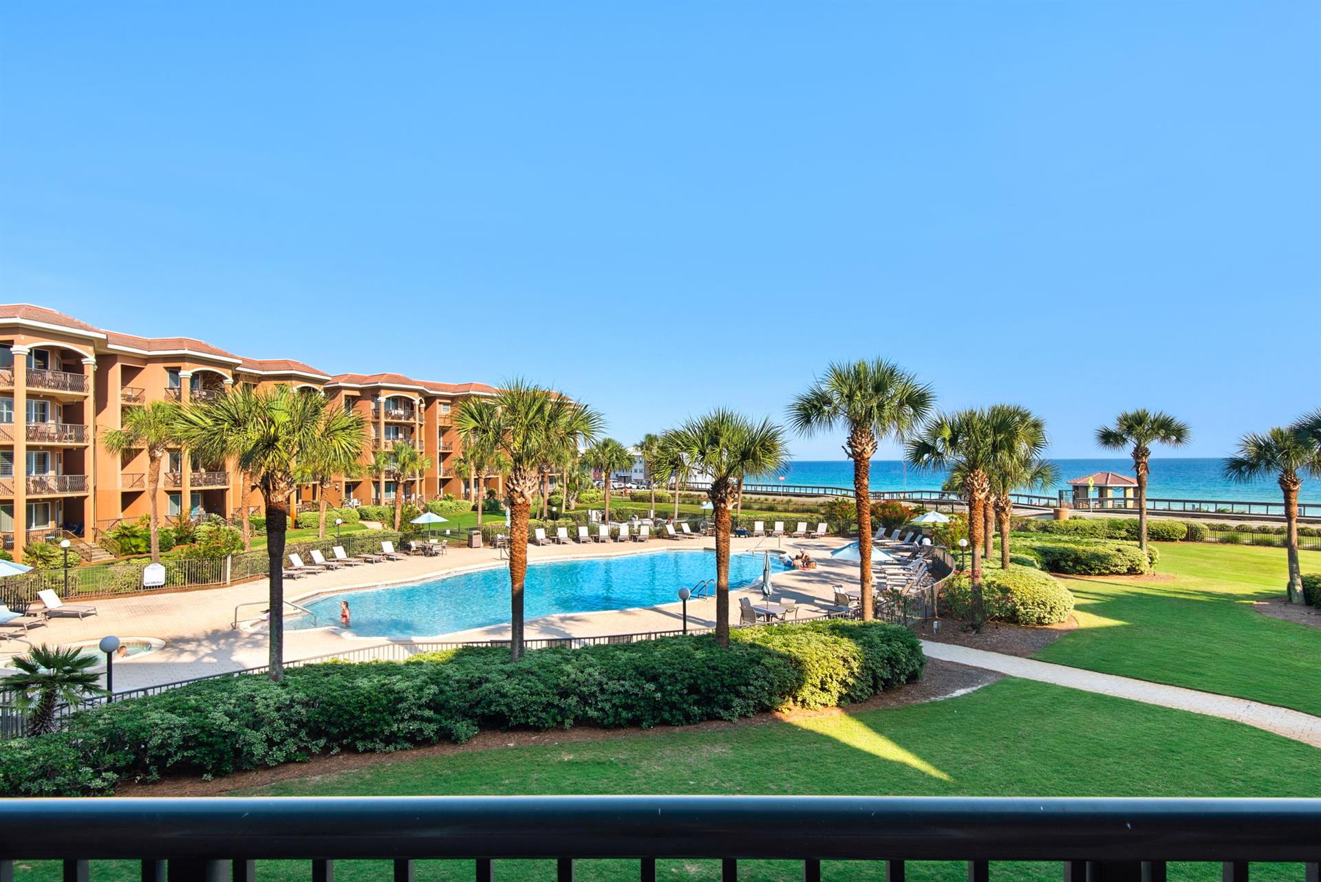 Beachfront property with a sparkling pool, lush landscaped grounds, and direct ocean access overlooking turquoise waters.