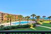 Beachfront property with a sparkling pool, lush landscaped grounds, and direct ocean access overlooking turquoise waters.