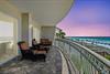 Spacious beachfront balcony with comfortable seating overlooking white sand and turquoise waters, perfect for sunset cocktails after a beach day.