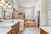 Unwind in the spacious primary bathroom featuring a soaking tub, walkin shower, dual vanities, and warm natural light streaming through frosted windows.