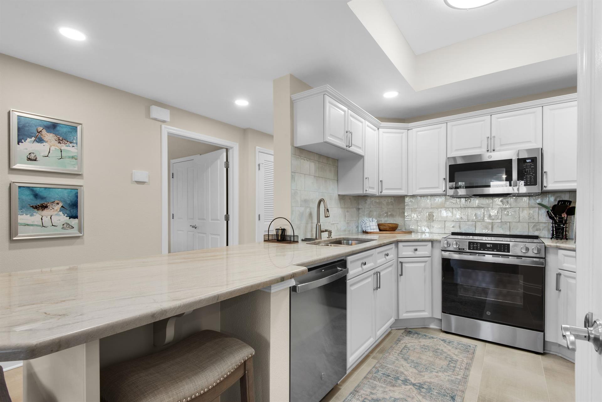 The kitchen features bright white cabinetry, gleaming countertops, and modern appliances.