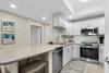 The kitchen features bright white cabinetry, gleaming countertops, and modern appliances.