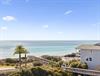 Coastal property featuring direct beach access via boardwalk, tropical landscaping, and stunning ocean views in a serene beachfront community.