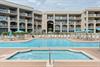 Beachfront resort featuring a sparkling pool, hot tub, and multiple balconies under sunny skies—your coastal retreat awaits.