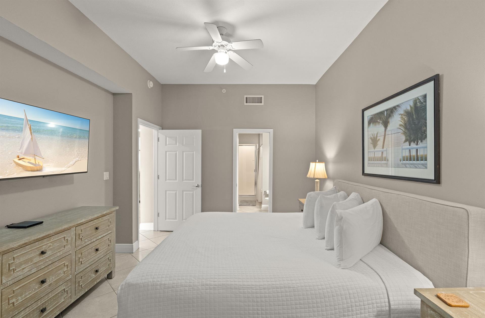 Drift off to sleep in this serene bedroom with coastal touches. Plush bedding, coastal artwork, and a ceiling fan create your perfect retreat after a day of adventure.