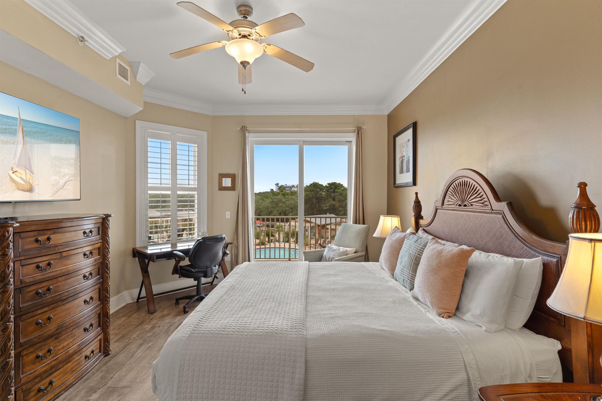 The inviting King bedroom features a plush bed, calming coastal touches, and sliding doors opening to your private balcony with pool and lake views, perfect for restful mornings.