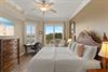 The inviting King bedroom features a plush bed, calming coastal touches, and sliding doors opening to your private balcony with pool and lake views, perfect for restful mornings.