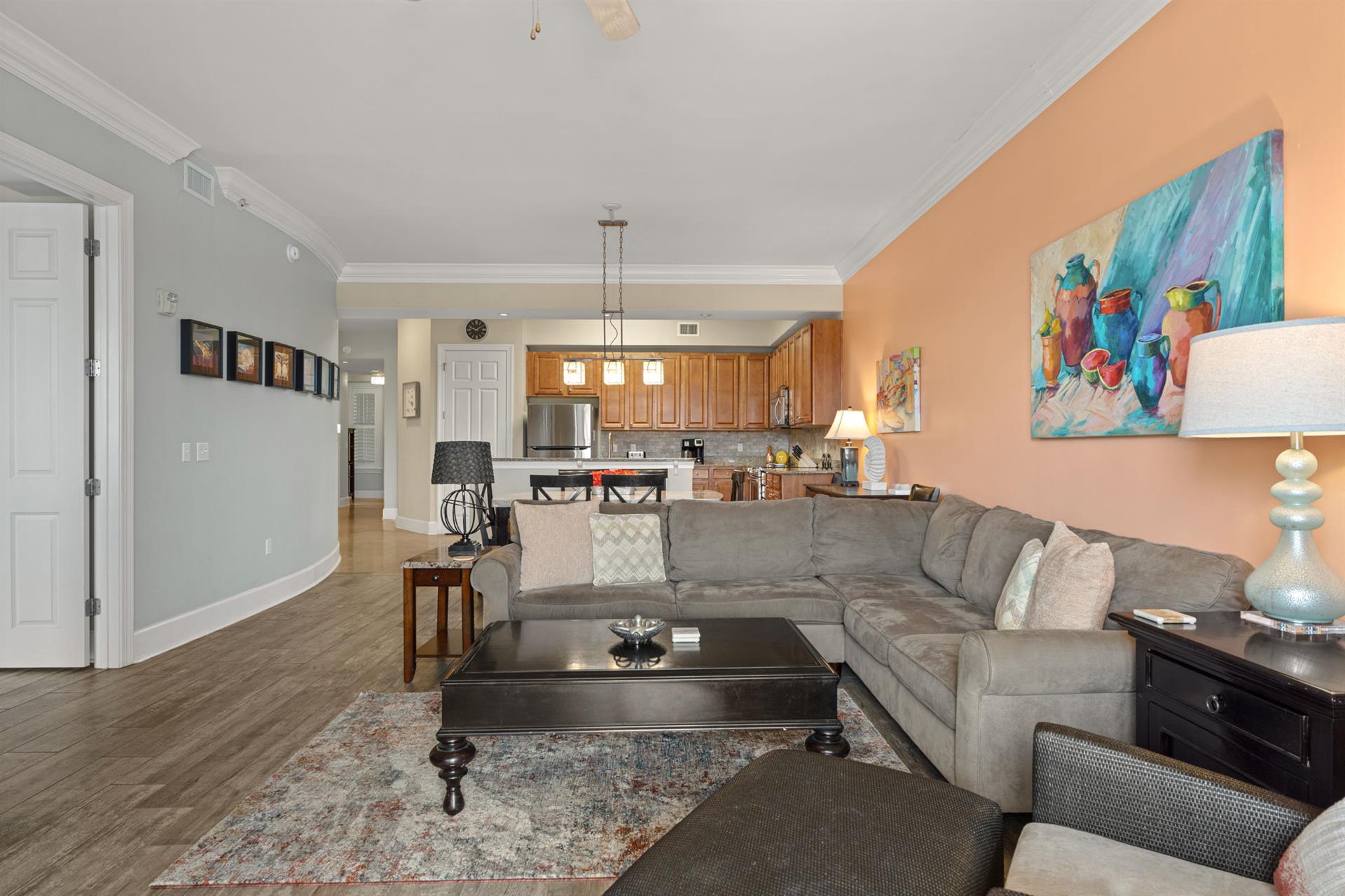 Spacious living area with sectional, enjoy vibrant coastal art, and let the open layout connect you to the fullyequipped kitchen.