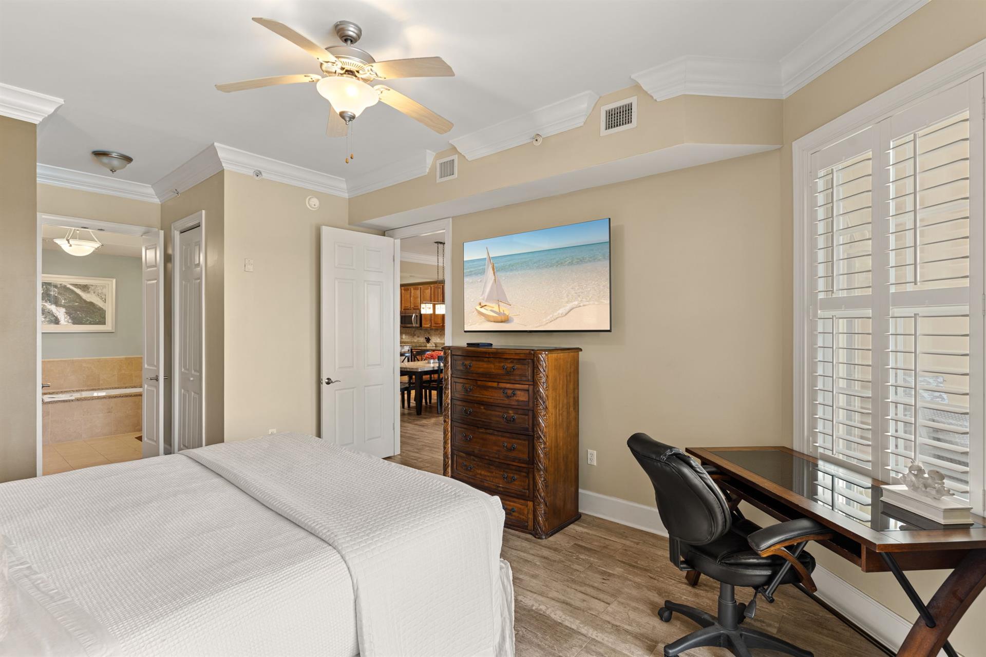 Peaceful king bedroom retreat features a plush bed, ceiling fan for comfort, and elegant coastal artwork that sets the tone for your relaxing getaway.