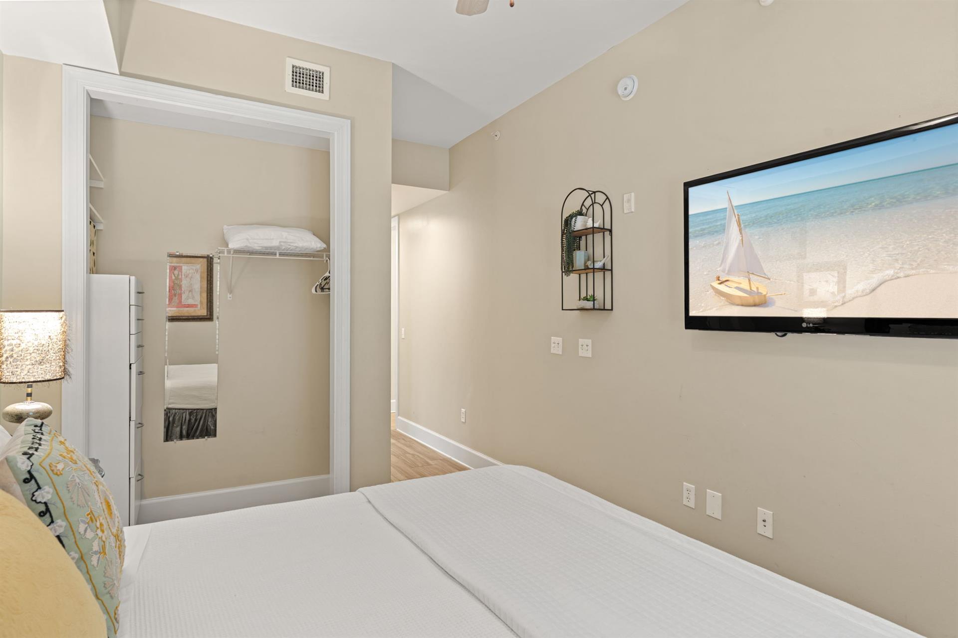 Serene king guest bedroom features a plush bed, vaulted ceilings, and wallmounted TV. Natural light and coastal artwork create a relaxing retreat after your days adventures.