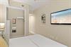 Serene king guest bedroom features a plush bed, vaulted ceilings, and wallmounted TV. Natural light and coastal artwork create a relaxing retreat after your days adventures.