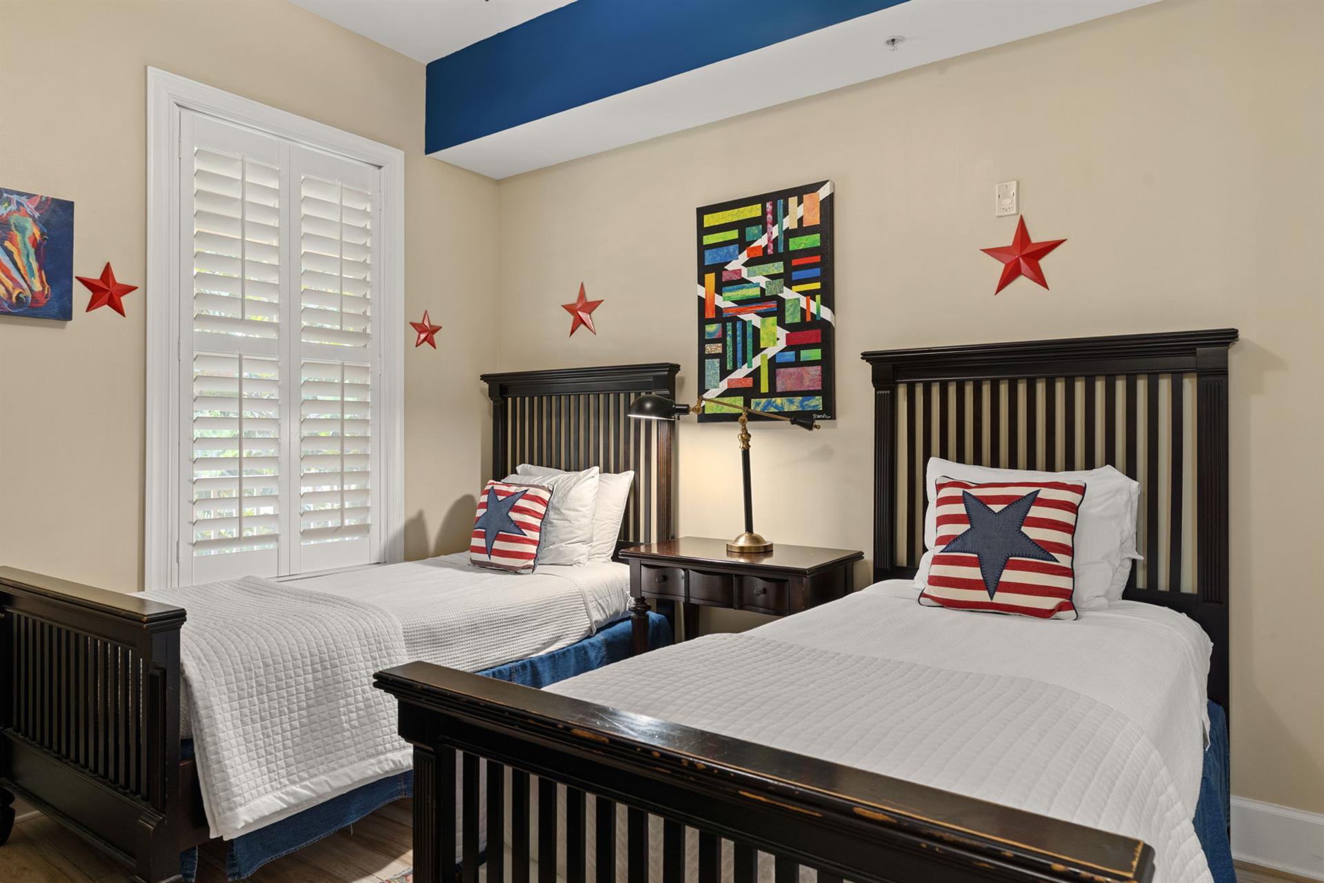 Rest easy in this cheerful room featuring two twin beds dressed in crisp linens, playful red star accents, and colorful artwork that adds a touch of fun to your home away from home.