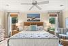 Sink into this coastalinspired primary bed and unwind beneath the gentle breeze of the ceiling fan as soft morning light filters through your windows.