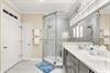 The elegant primary bathroom features a spacious walkin shower with marble tile, dual vanity sinks, and designer fixtures that blend style with comfort.