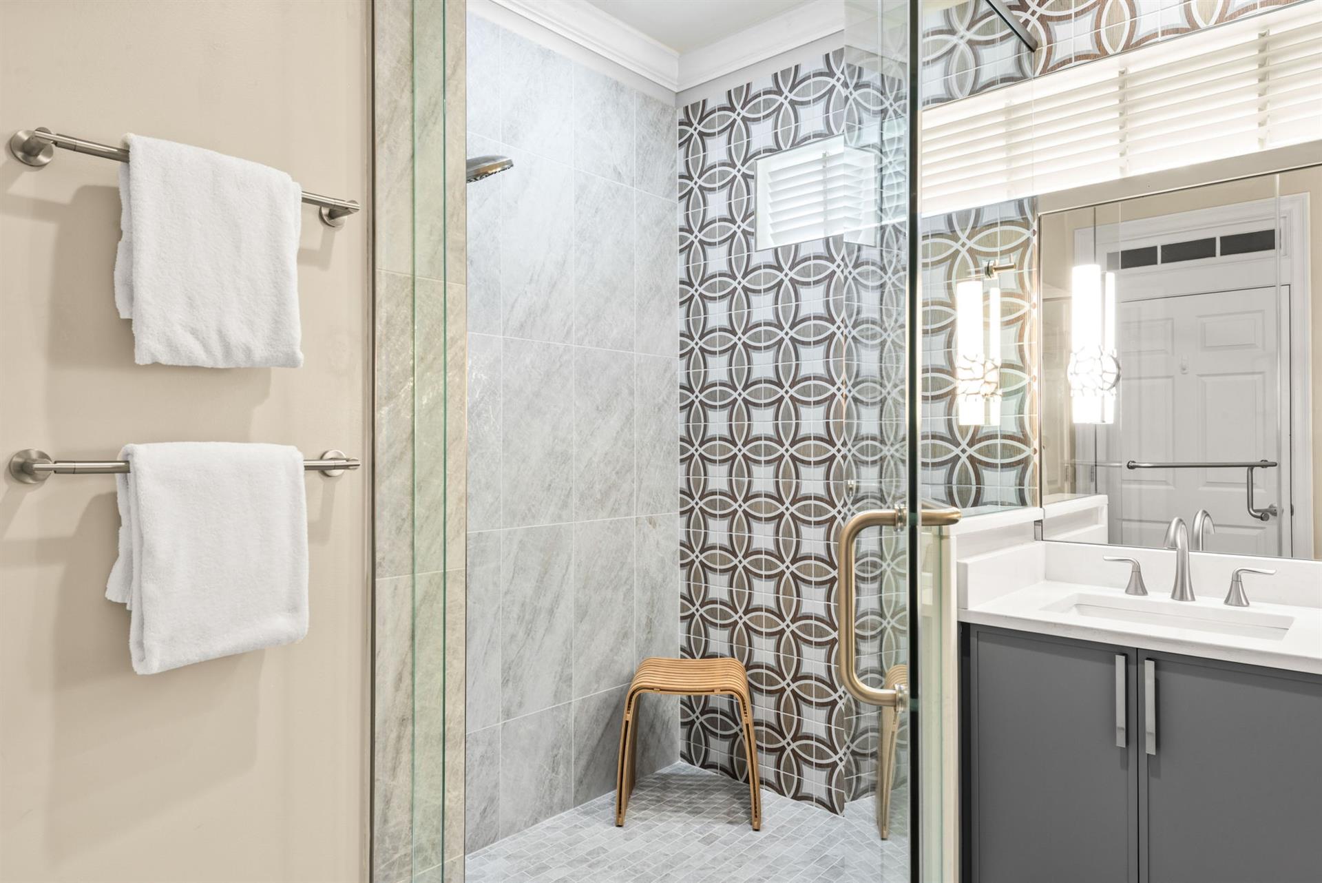 Refresh in the spacious walkin shower featuring elegant marble tile and a stylish geometric accent wall.
