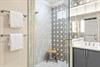 Refresh in the spacious walkin shower featuring elegant marble tile and a stylish geometric accent wall.