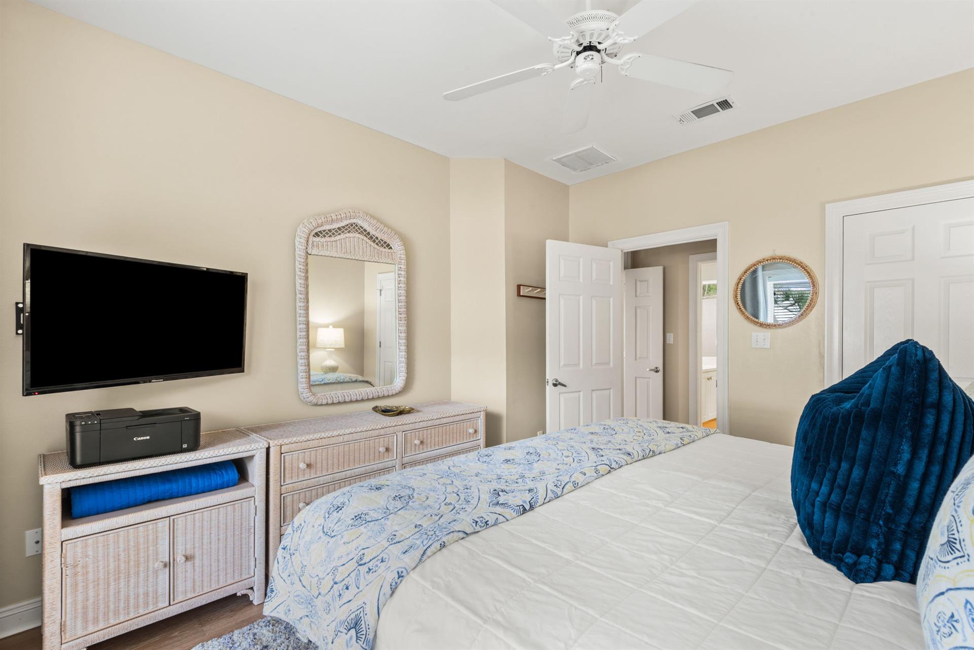 Unwind in your serene bedroom, featuring flatscreen TV, ceiling fan, and coastalchic décor.