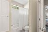 The bathroom features a refreshing showertub combo with crisp white tiling, soft natural light from above.