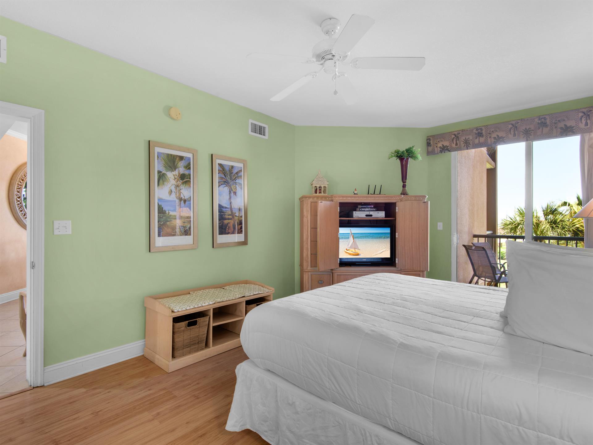 The serene bedroom with ceiling fan comfort and entertainment at your fingertips. Sliding doors lead  to the private balcony.