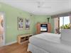 The serene bedroom with ceiling fan comfort and entertainment at your fingertips. Sliding doors lead  to the private balcony.