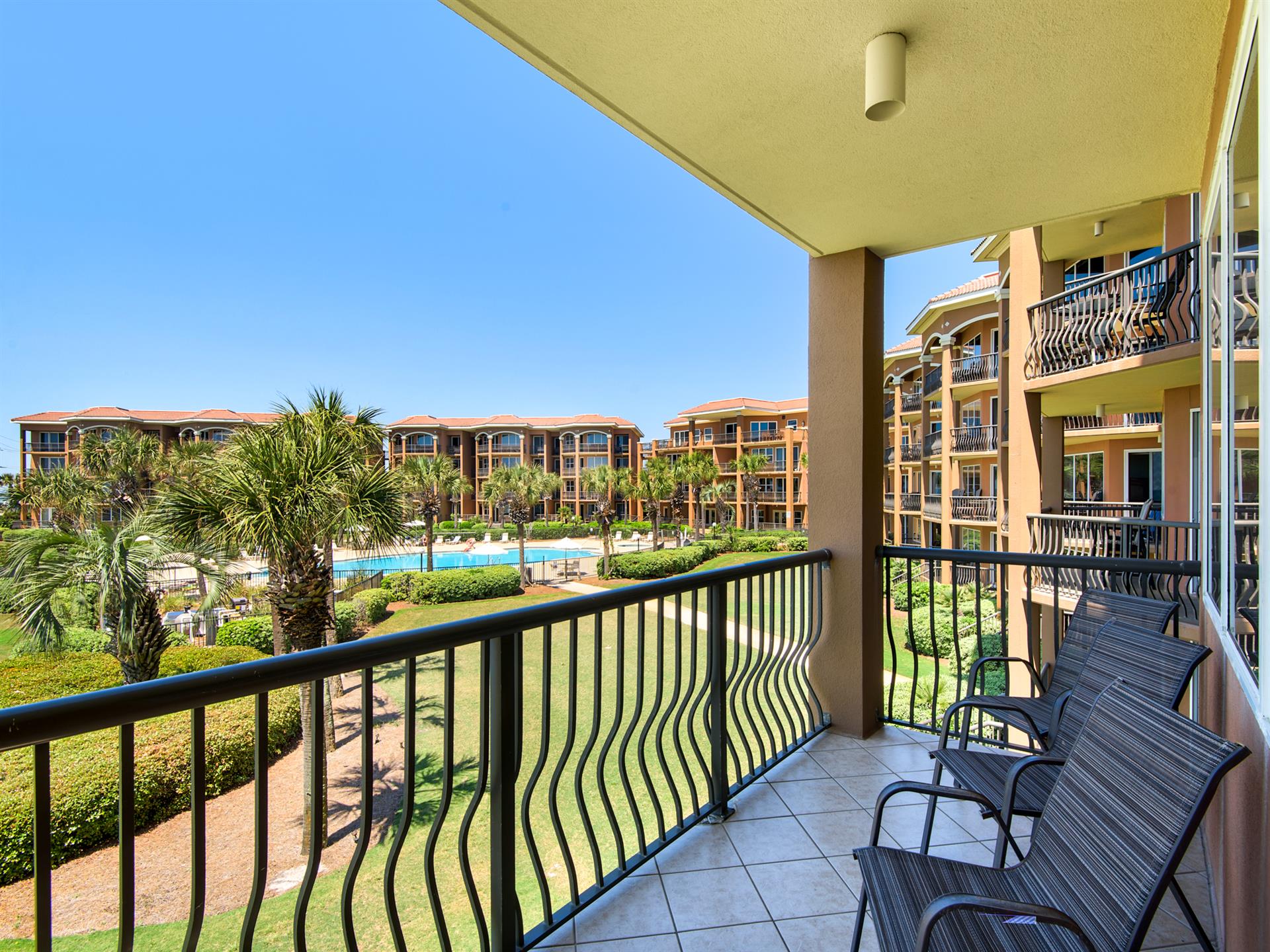 The private balcony overlooks lush gardens and sparkling pools.