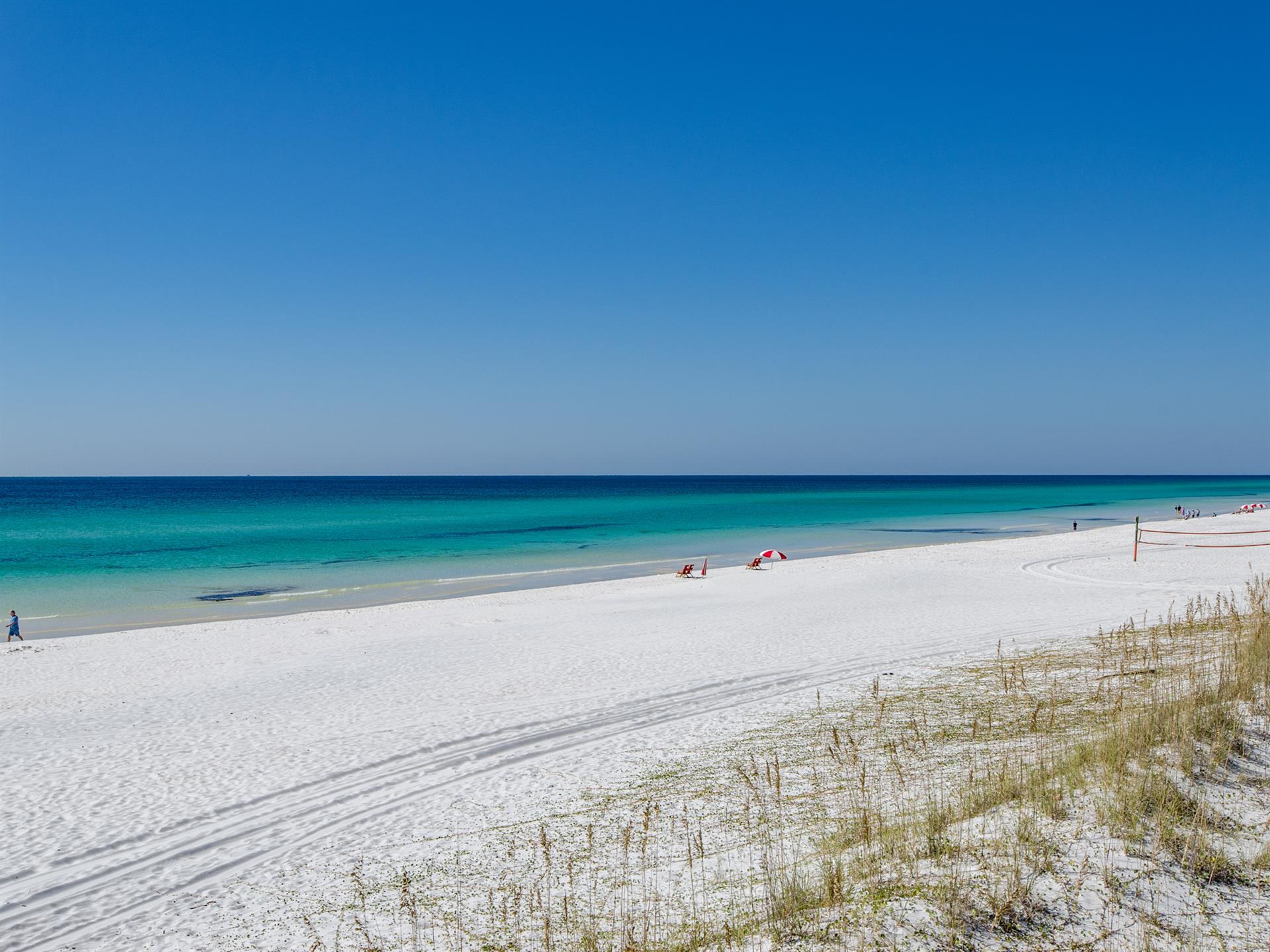 Pristine white sand beach stretches along turquoise waters.