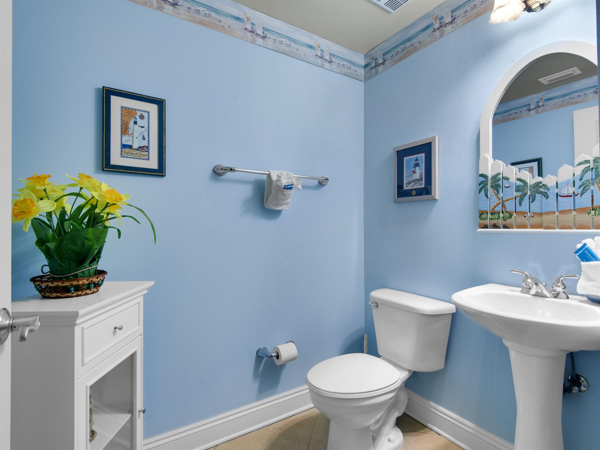 Freshen up in this convenient half bath featuring crisp white fixtures and nautical artwork