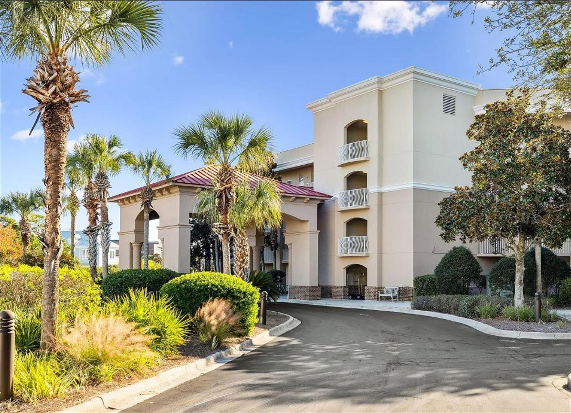 A welcoming property nestled among lush palm trees and manicured landscaping, featuring Mediterraneaninspired architecture with a covered entrance and multiple balconies overlooking beautifully maint