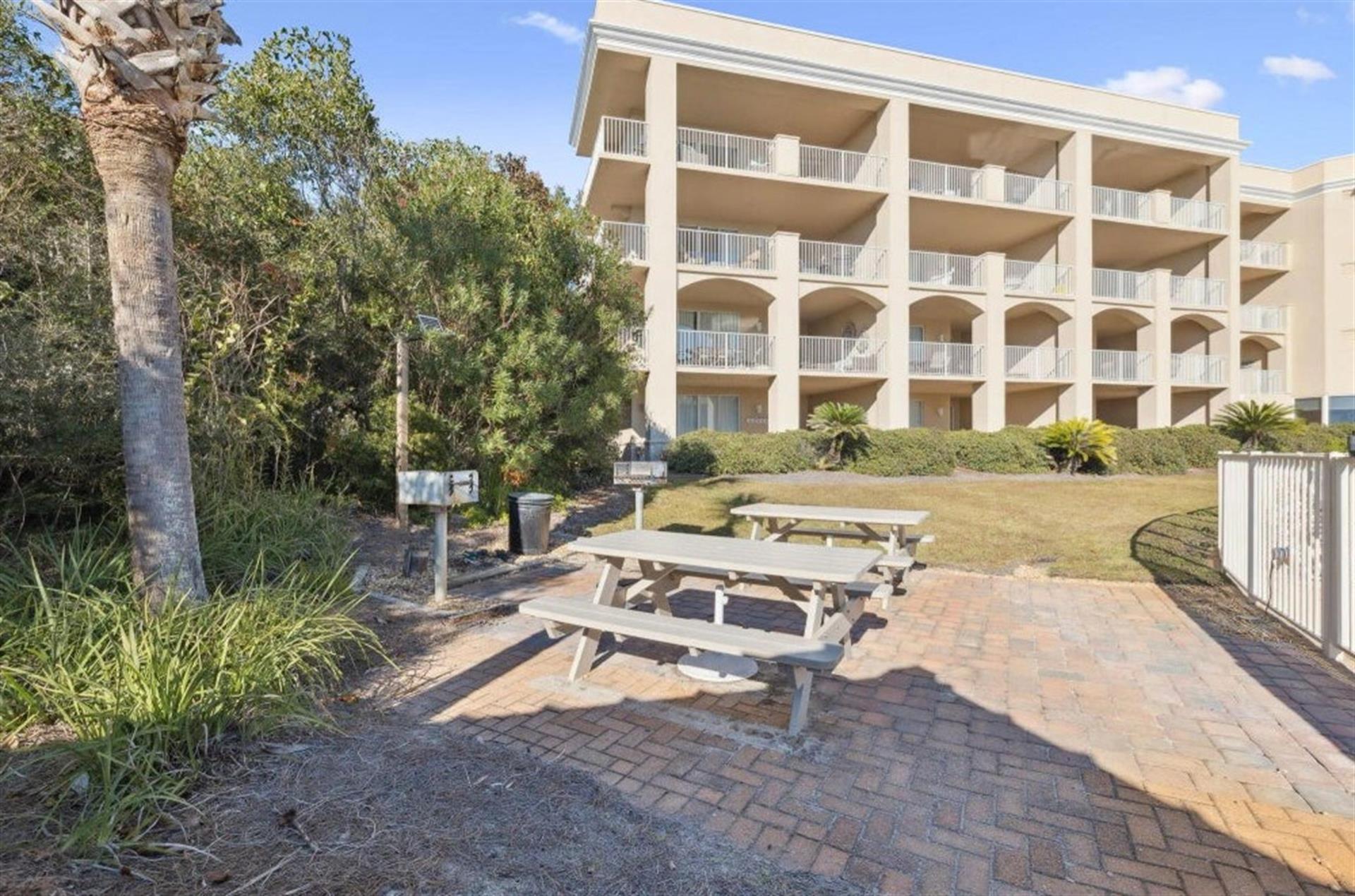 The property building features balconies overlooking lush tropical landscaping and a convenient picnic area with shaded seating—perfect for outdoor relaxation.