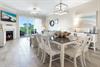 Your openconcept living and dining area features coastal elegance with a cozy fireplace, oceanview balcony access, and seating for eight beneath soft lighting, perfect for relaxed evenings together.