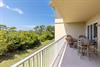 A spacious outdoor terrace overlooks lush coastal greenery under clear blue skies, offering the perfect spot to dine al fresco or simply unwind.