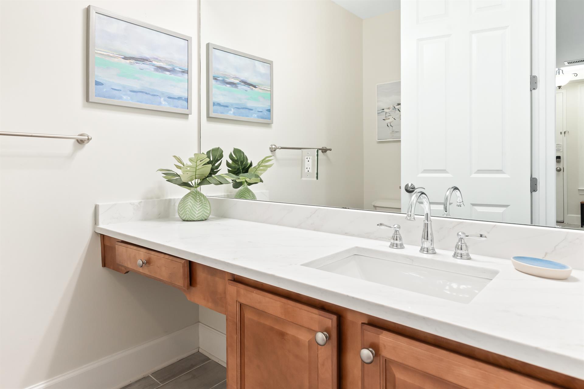 Refresh in your bright, stylish bathroom with coastalinspired art, warm wood accents, and a pristine vanity designed for your comfort.