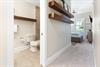 Your private retreat features open floating shelves, a cozy seating nook, and an ensuite bathroom with a walkin shower, all bathed in soft natural light.