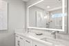 Bathroom 1 with dual sinks set in beautiful marble countertops, a bright LED mirror, and a sleek glassenclosed shower.