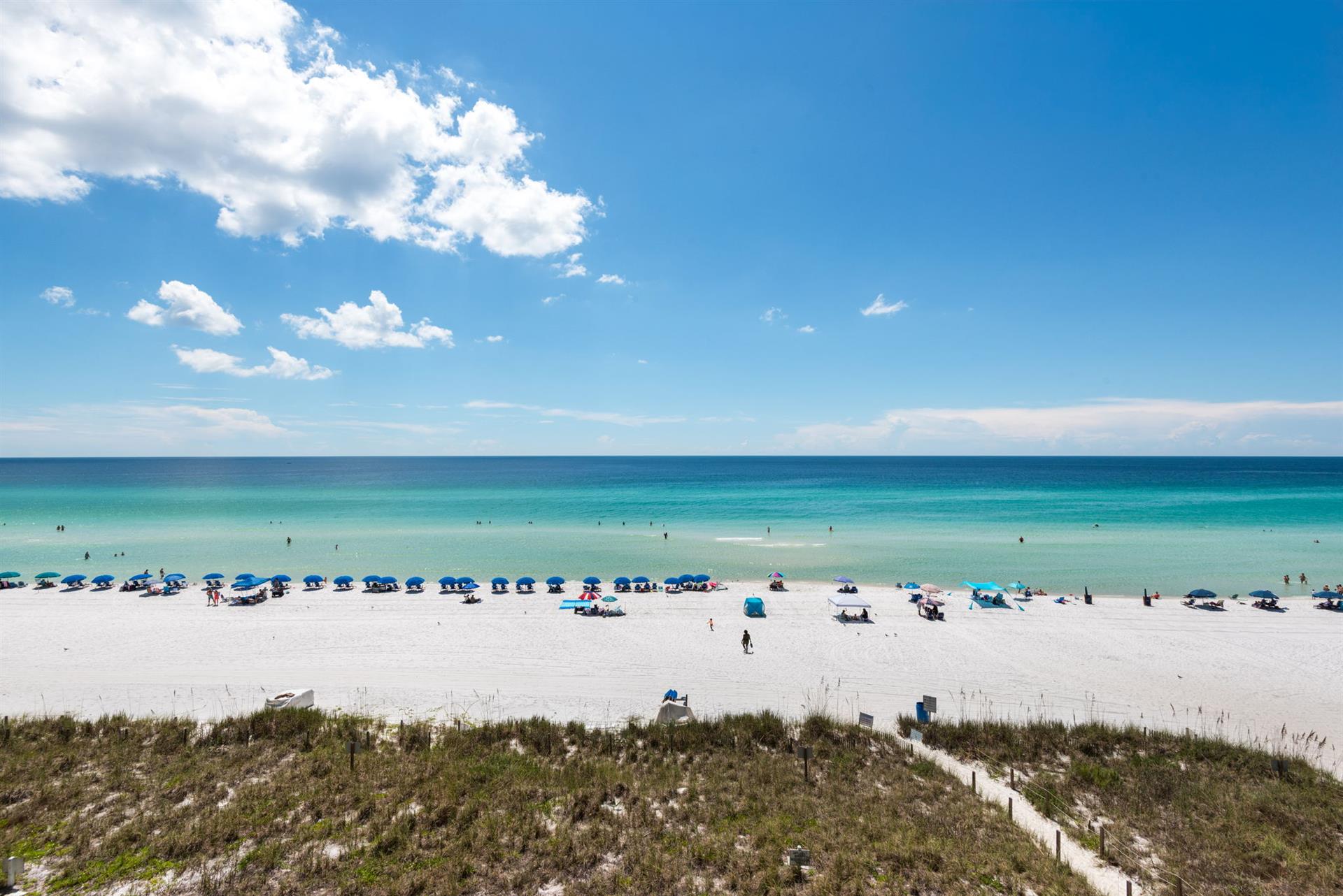 The property is located near a stunning beach featuring powdery white sand, turquoise waters, and colorful umbrellas dotting the shore—a perfect backdrop for your Gulf Coast getaway.