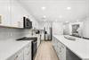 Your bright, fullyequipped kitchen awaits with sleek white cabinetry, gleaming countertops, and goldaccent hardware—perfect for preparing meals in style.