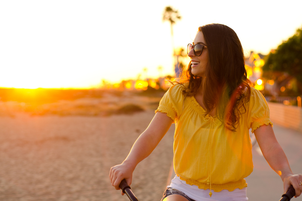 woman laughing on a bike on the beach
