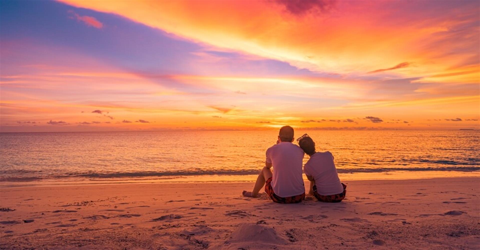 Two people sitting on the beach viewing a Destin sunset