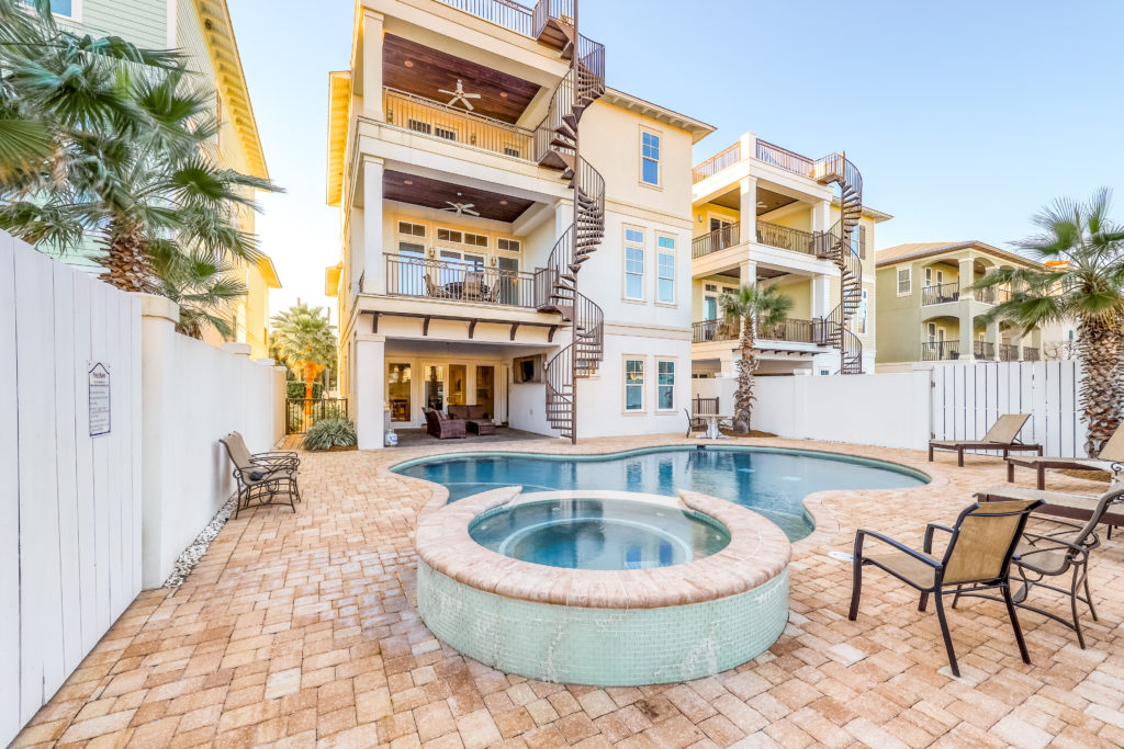 Exterior of the Sunset Manor home with fenced-in yard, swimming pool, and hot tub in Destin, Florida.