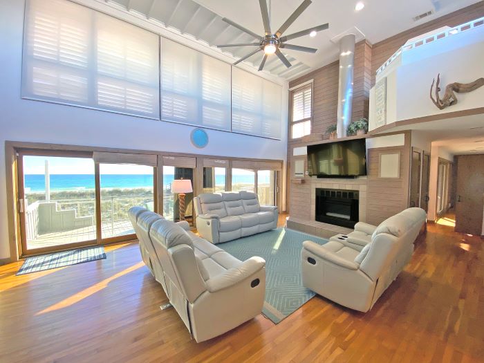 The Oyster beach house in Navarre Beach, Florida's living room with a wall of windows providing sweeping views of the beach.