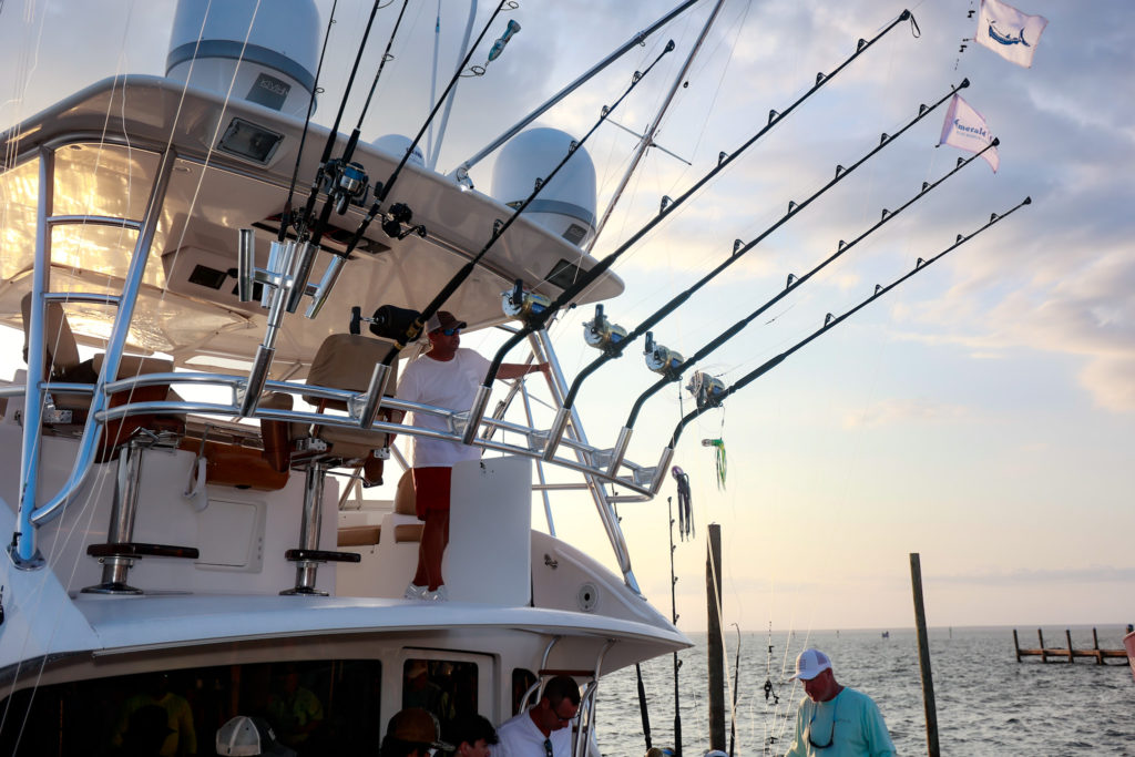 Men on the back of a large fishing boat equipped with lots of rods and reels