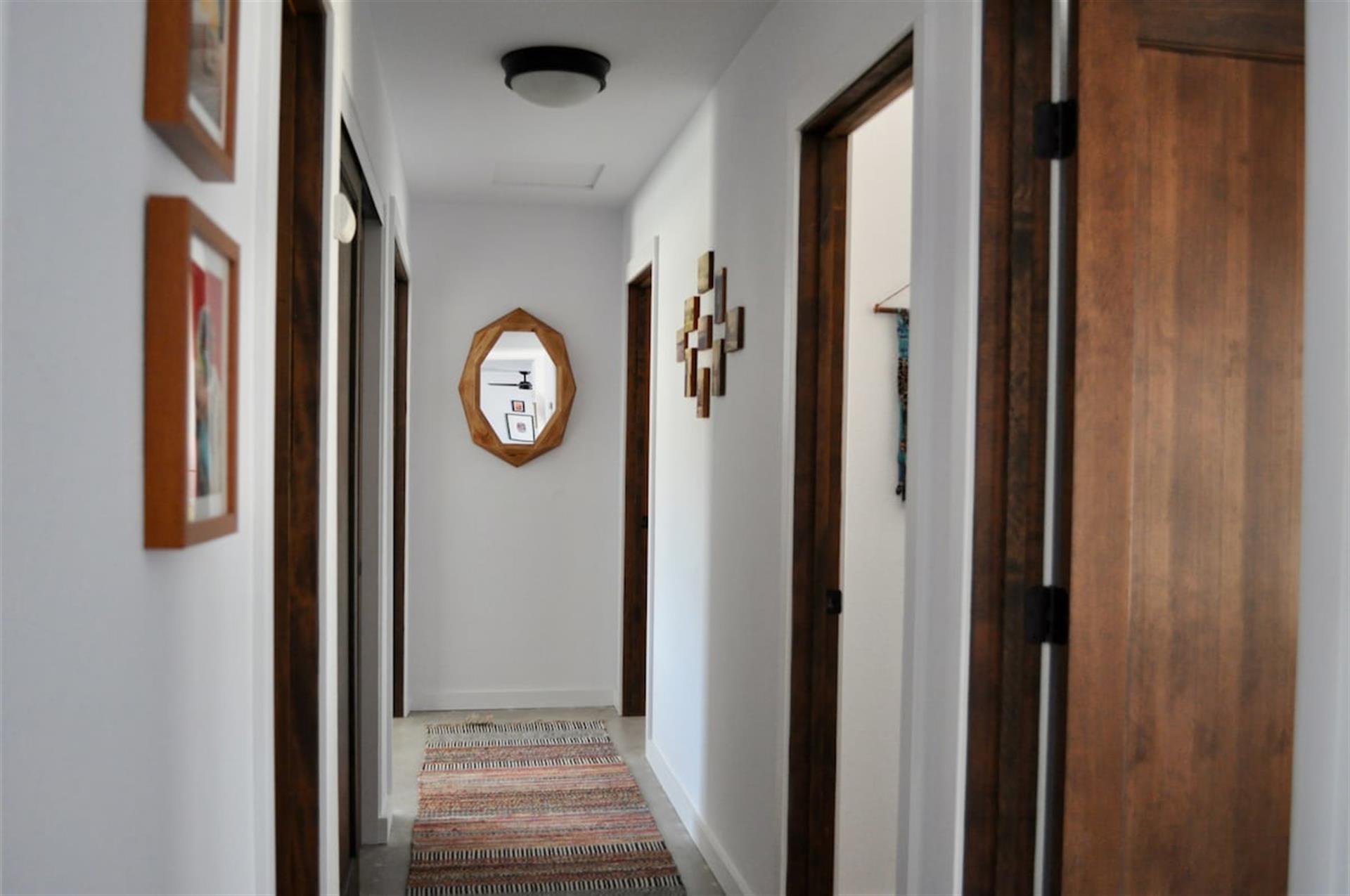 Hallway of bedrooms. On left guest bathroom, locked hall closet and master bedroom. On the right small wellness room, bedroom 3 and bedroom 2.