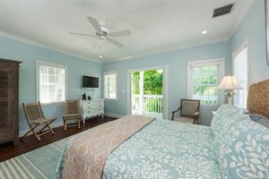 This spacious bedroom has a dresser, TV, and ceiling fan.