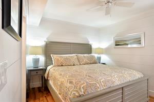 King bedroom with ceiling fan and bedside lighting.