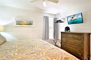 King bedroom has TV, dresser and ceiling fan.