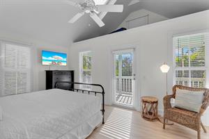Primary bedroom with TV, ceiling fan, and seating.